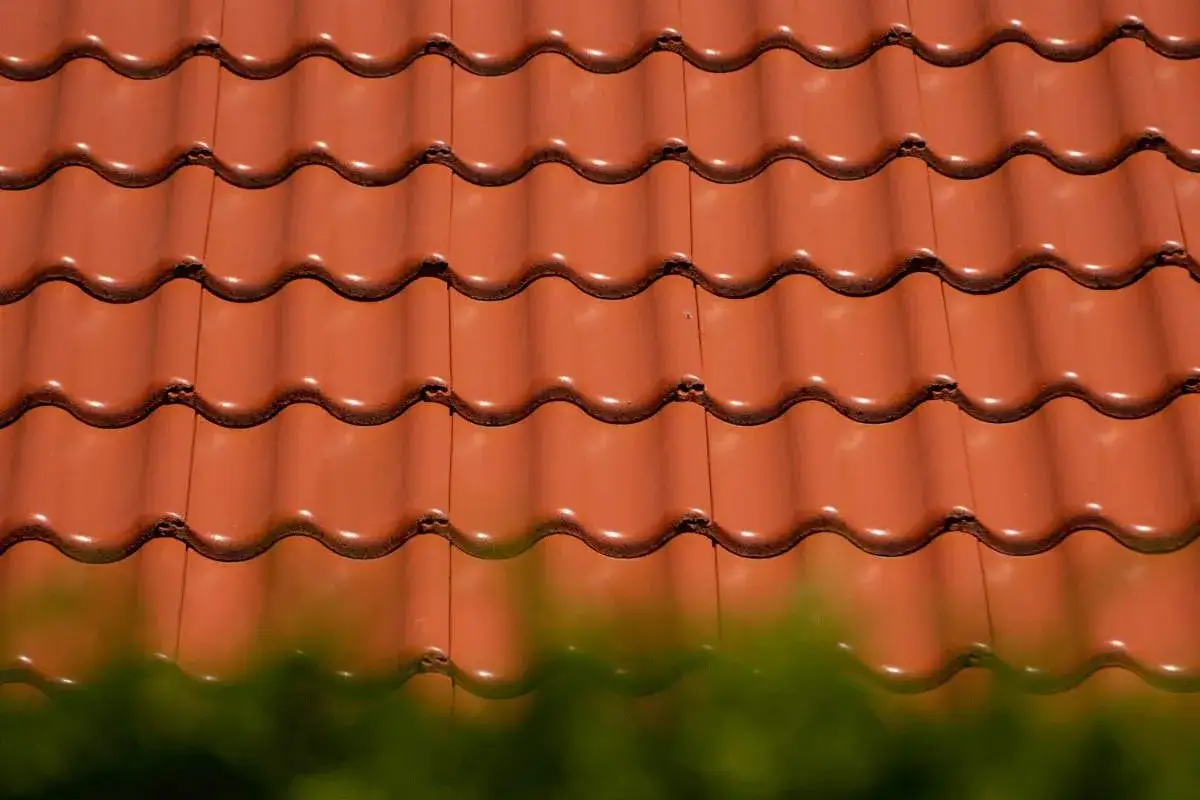 Czerwone, faliste dach&oacute;wki ceramiczne tworzą gładką, jednolitą powierzchnię. R&oacute;żne rodzaje dach&oacute;wek mogą nadać budynkowi unikalny charakter.