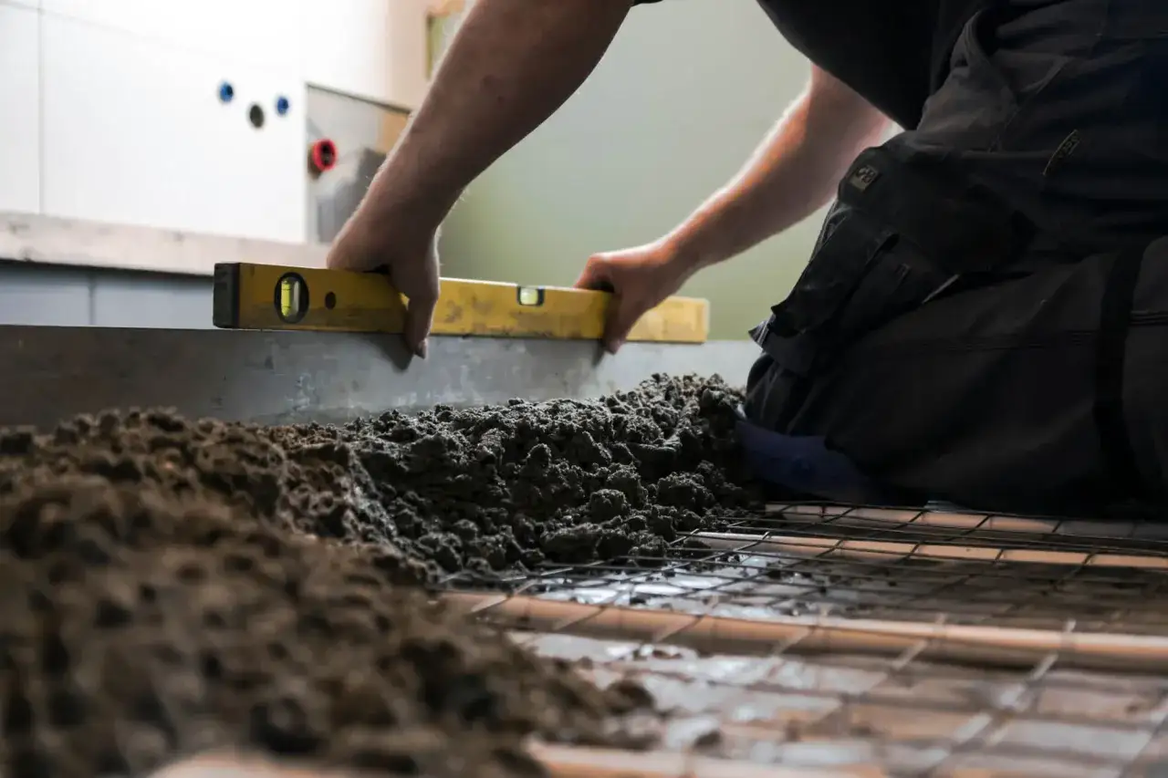 Budowlaniec sprawdza poziom wylewki, która będzie idealnym gruntem pod płytki.