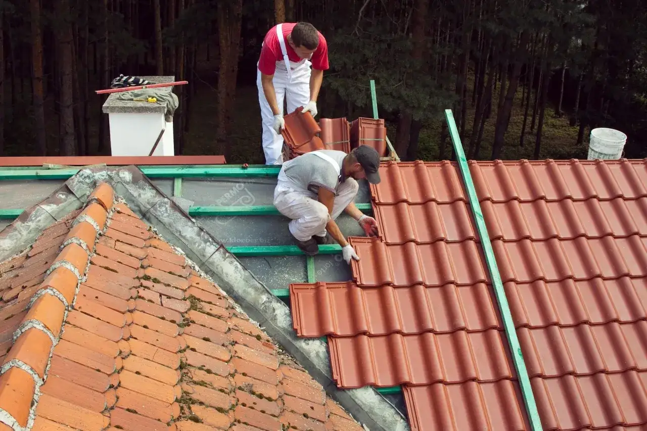 Dw&oacute;ch dekarzy układa nowe dach&oacute;wki. Zastanawiasz się, ile dach&oacute;wek na m2 potrzeba do pokrycia dachu?